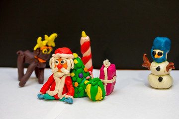 Plasticine Santa Claus resting near the Christmas tree with his friends