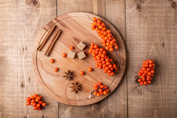 Sea-buckthorn berries and spice on wooden background. Rustic style.