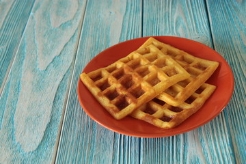 Homemade waffles are on an orange plate.