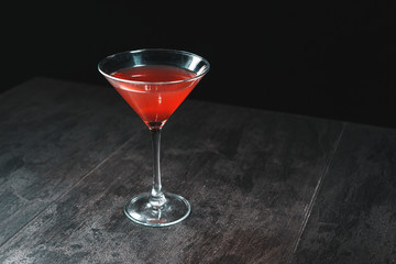 Cosmopolitan cocktail in nice red color in front of a black background