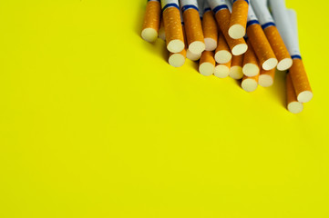 Heap of cigarettes with tobacco and filter scattered on yellow background with copy space for your text or logo. Stop smoking concept