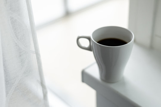 A cup of coffee on the windowsill. Big window. Scandinavian style
