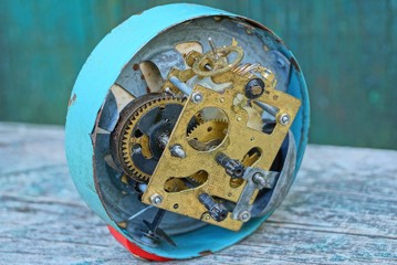 big old clock alarm clock with an open mechanism on a gray table