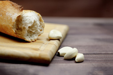 Sliced French baguette and garlic on wooden Board