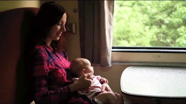 Young mother with infant baby on the hands are happy and traveling by train