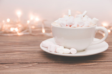 hot chocolate with marshmallow candy and Christmas decorations garland on a wooden background