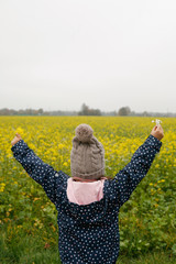 Girl with Open Arms Standing In Front Of Canola Field