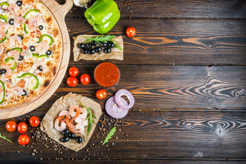 Fototapeta na wymiar Food background design. Seafood, shrimps and olives on a dark wood. Pizza ingredients.
