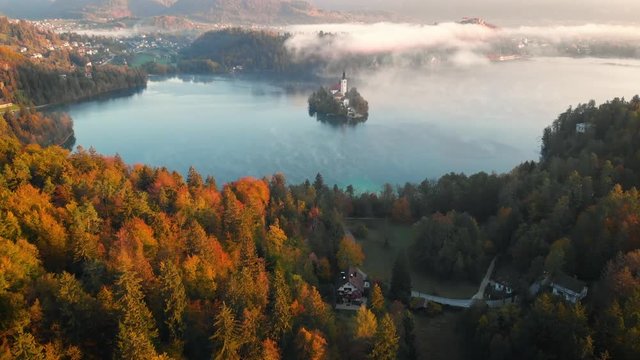 4K Flying around romantic Bled lake with chapel on the island at foggy sunrise