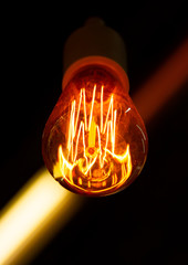 Edison lamp design on a dark background. Edison diode bulb. Glowing Edison bulb spiral on a black...