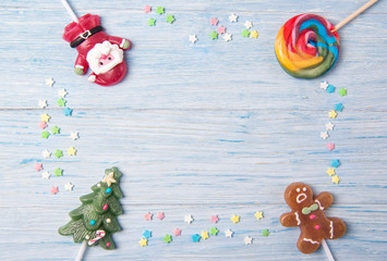 Sweet candies on a stick in shapes of Christmas tree, Gingerbread man and Santa Claus, Christmas frame on a wooden background