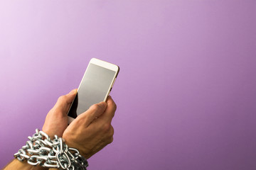 Mobile phone chained to the hands of a man.  Addiction to smartphone or mobile devices concept.