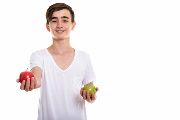 Studio shot of young happy Persian teenage boy smiling while giv