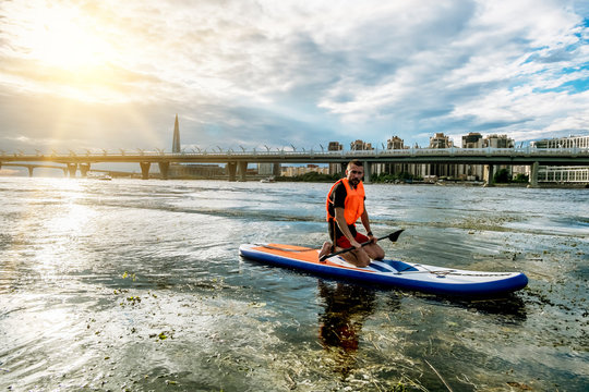 man floats on the sup paddle board on the river opposite the  ring road and the skyscraper Lakhta in St. Petersburg