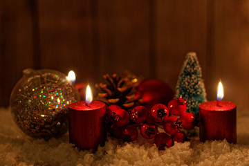 Christmas decoration - three burgundy burning candles, baubles, cone, tree and rowan 