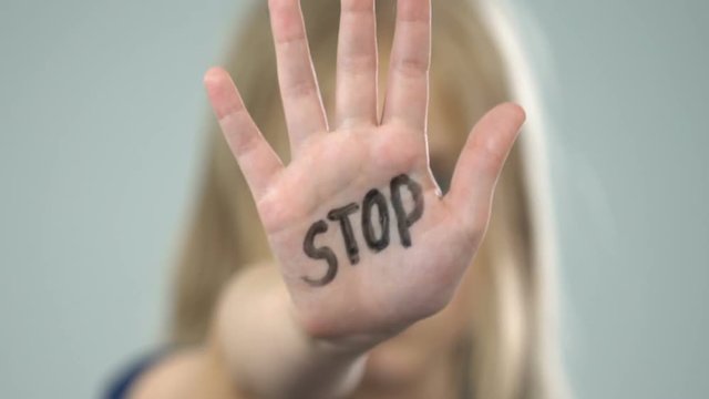 Scared young girl showing stop sign, domestic violence victim, abuse awareness