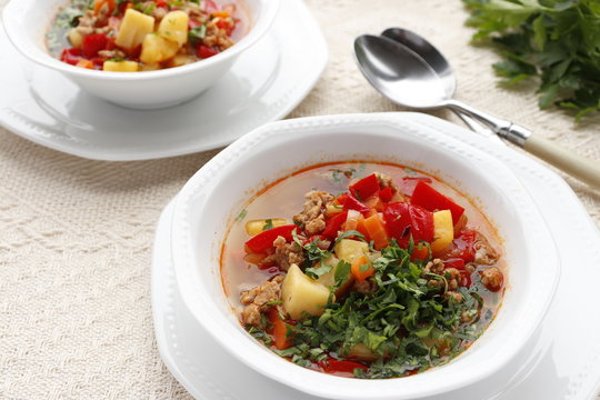 Bulgarian potato soup with paprika and minced meat. Two white bowls