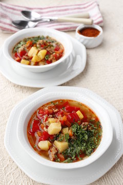 Bulgarian potato soup with paprika and minced meat. Two white bowls