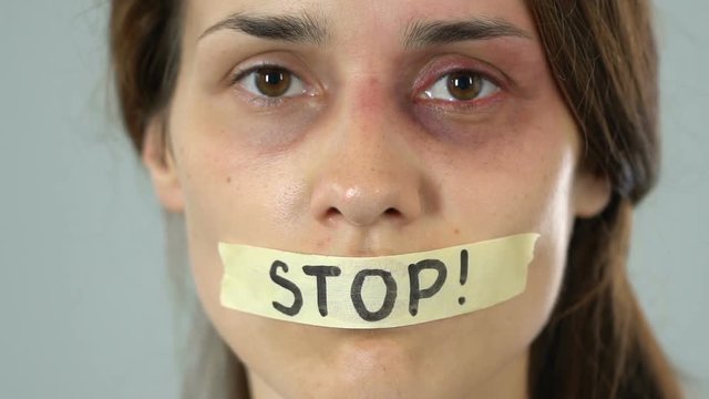 Stop message on taped mouth of bruised woman, helpless silent abuse victim