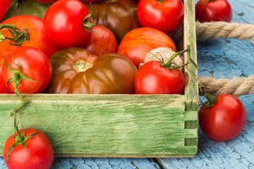 Set of different sorts of ripe tomatoes in the wooden tray