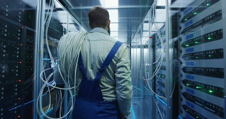 Wide movement stabilized shot of two people working in a data center carrying cable to repair rows of server racks and discuss their work