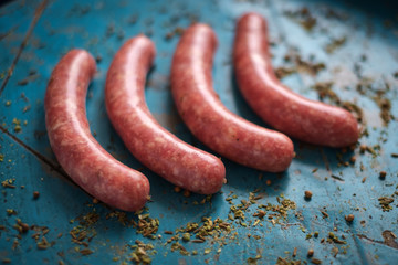 natural homemade raw pork and beef sausages with seasoning on blue wooden background