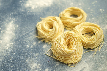 Raw homemade spaghetti nest with flour on a grey background. Fresh Italian Cappellini pasta