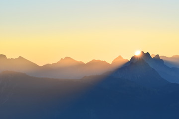Colorful sunrise over the mountains in the Allgaeu Alps at the border region of Germany and Austria. Silhouettes of mountain ranges with yellow sky. Zugspitze in the background. Copy space.