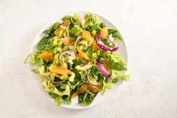 healthy salad from tangerines and lettuce with red onions on a bright background with copy space, high angle view from above