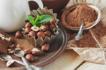 Piece of chocolate cake, mint leaves, hazelnuts and jar with milk
