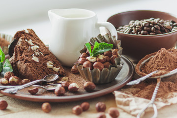Piece of chocolate cake, mint leaves, hazelnuts and jar with milk
