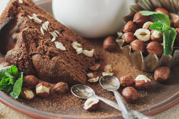 Piece of chocolate cake, mint leaves, hazelnuts and jar with milk