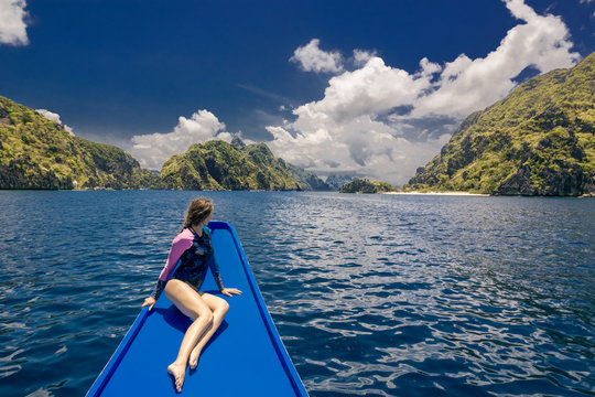 Young woman on the boat and looking forward into lagoon. Travelling tour in Asia: El Nido, Palawan, Philippines.