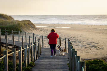 Middle-Aged Woman Walks Dog on Boardwalk