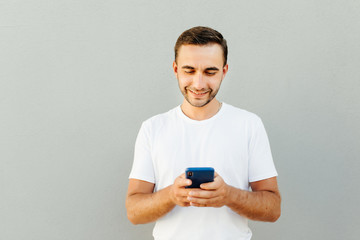 Portrait of excited using smartphone for getting sending sms isolated on gray background