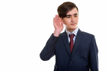 Studio shot of young handsome Persian teenage businessman listen