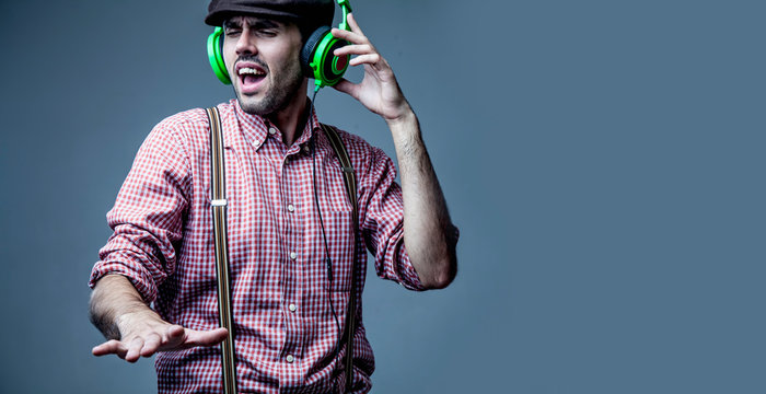 Handsome man dj with closed eyes in fashionable retro styled wear and headphones listening to the music.