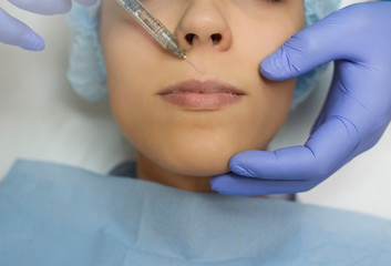 Top view of lips augmentation procedure on a young woman done by a cosmetologist doctor with...
