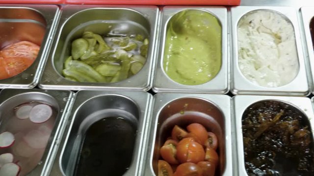 Cooking hamburger. Panorama of cheese, green chilli, pickled cucumber, onion, sauce, cherry tomatoes, radish. 4K