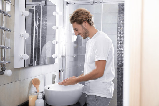 Young Man Washing Hands In Bathroom. Using Soap