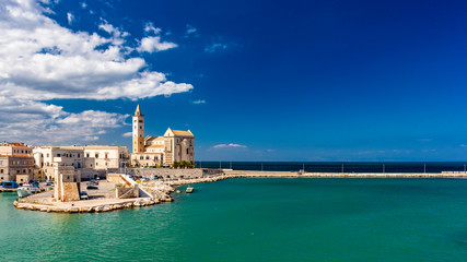 The beautiful Romanesque Cathedral Basilica of San Nicola Pellegrino, in Trani. Construction in limestone tuff stone, pink and white. A pointed arch under the bell tower. Italy, Puglia, Bari, Barletta - obrazy, fototapety, plakaty