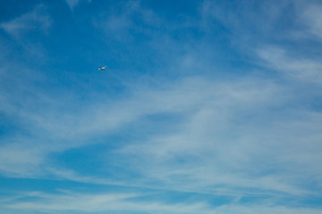 Airplane flying in the blue sky among clouds and sunlight