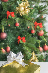 Decorated and blurred Christmas tree in the background and front gift box