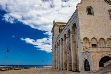 Fototapeta premium The beautiful Romanesque Cathedral Basilica of San Nicola Pellegrino, in Trani. Construction in limestone tuff stone, pink and white. A pointed arch under the bell tower. Italy, Puglia, Bari, Barletta