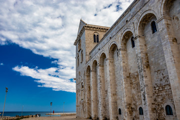Fototapeta premium The beautiful Romanesque Cathedral Basilica of San Nicola Pellegrino, in Trani. Construction in limestone tuff stone, pink and white. A pointed arch under the bell tower. Italy, Puglia, Bari, Barletta
