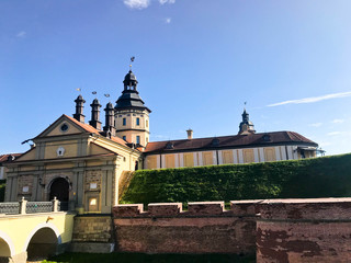 Old, ancient medieval castle with spiers and towers, walls of stone and brick surrounded by a protective moat with water in the center of Europe. Baroque style architecture