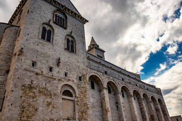 The beautiful Romanesque Cathedral Basilica of San Nicola Pellegrino, in Trani. Construction in limestone tuff stone, pink and white. A pointed arch under the bell tower. Italy, Puglia, Bari, Barletta