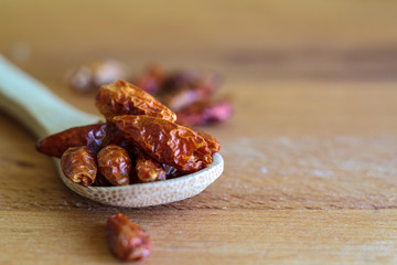 Spoon with Dried red chili on wooden board
