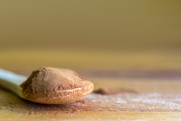 Wooden spoon with Cinnamon powder on a wooden board