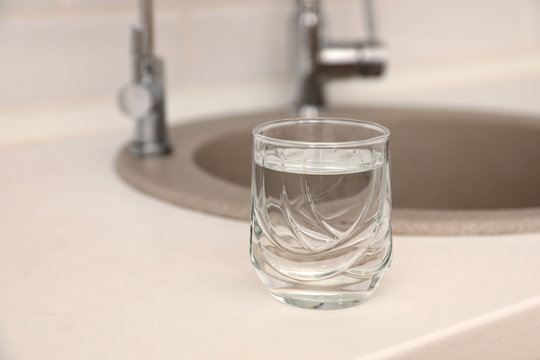Glass of water on counter near sink. Space for text